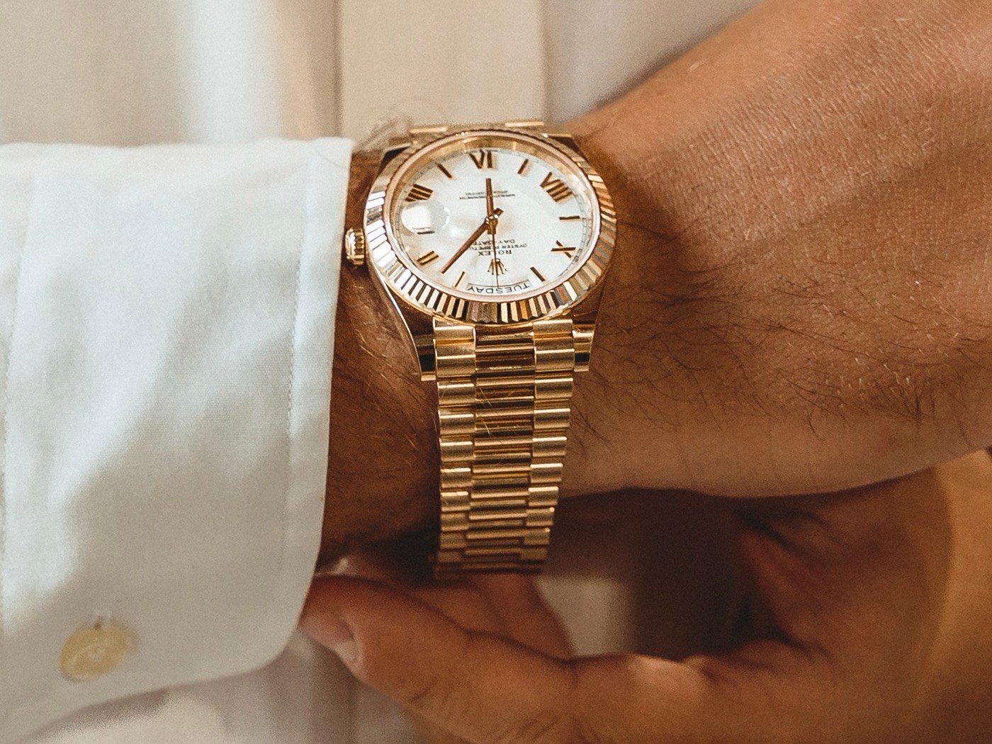 Orologio in oro con quadrante bianco indossato al polso, controllato da vicino