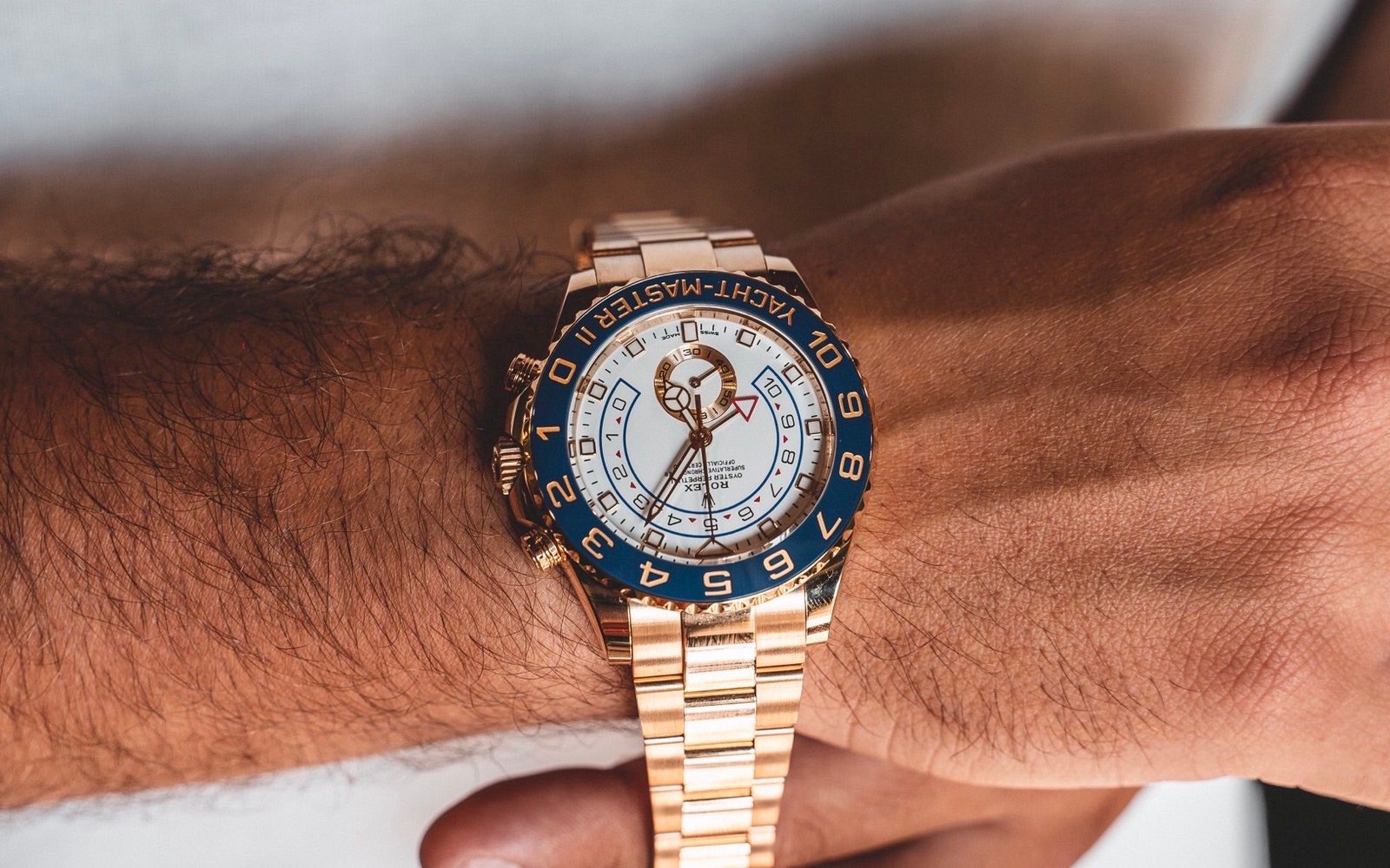 Orologio di lusso in oro con ghiera blu, indossato al polso